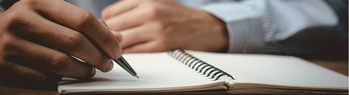Man writing on a notepad with a pen